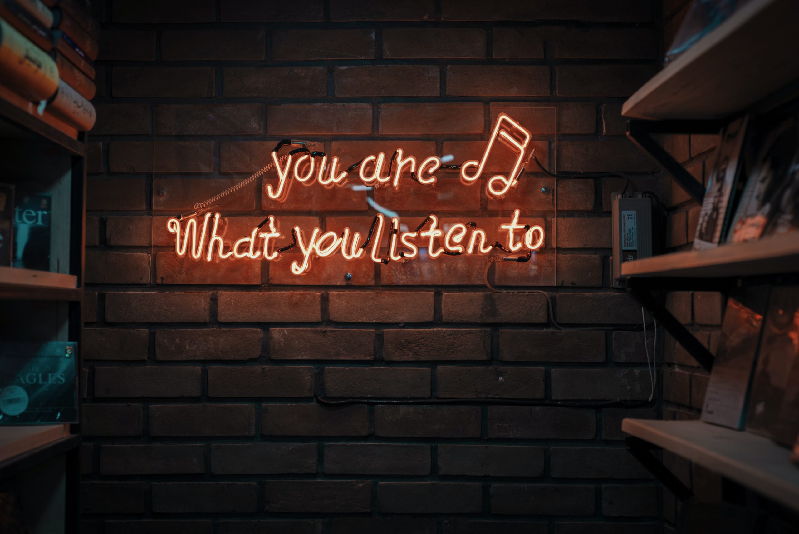 Mur en brique avec un luminaire formant la phrase " You are what you listen to"